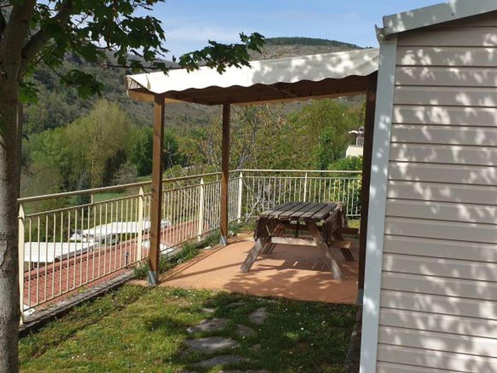 a patio with a picnic table and an umbrella at Mobil-home avec Terrasse, 3 Chambres, 4 Personnes - API-1-52-1131 in Saint-Rome-de-Tarn