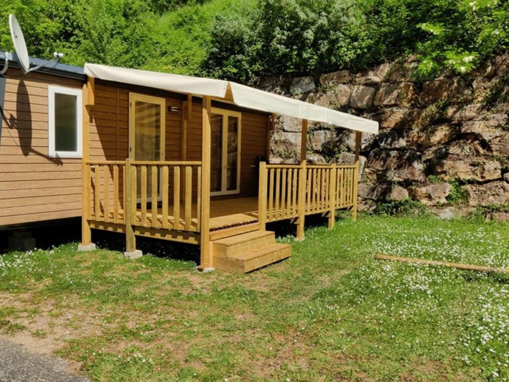 Mobil Home avec Terrasse - 4 personnes - API-1-52-1165 في Saint-Rome-de-Tarn: كابينة خشبية مع شرفة ومظلة بيضاء