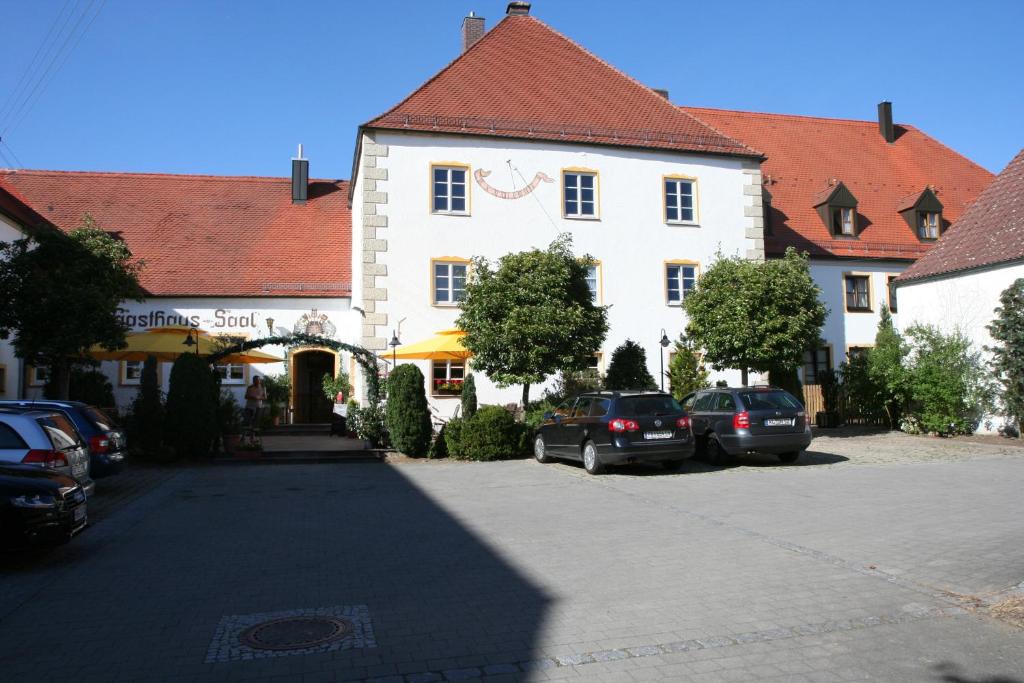 un gran edificio blanco con coches aparcados en un aparcamiento en Schlosswirt Etting, en Ingolstadt