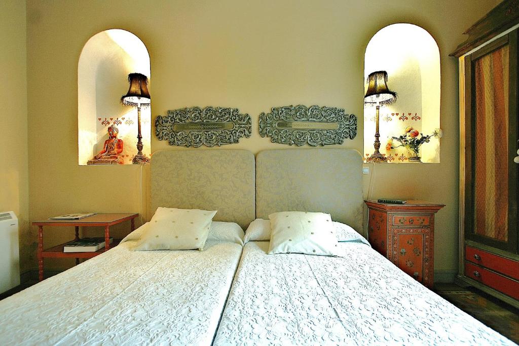 1 dormitorio con 1 cama blanca grande y 2 almohadas en Alameda Palacete, en Cáceres