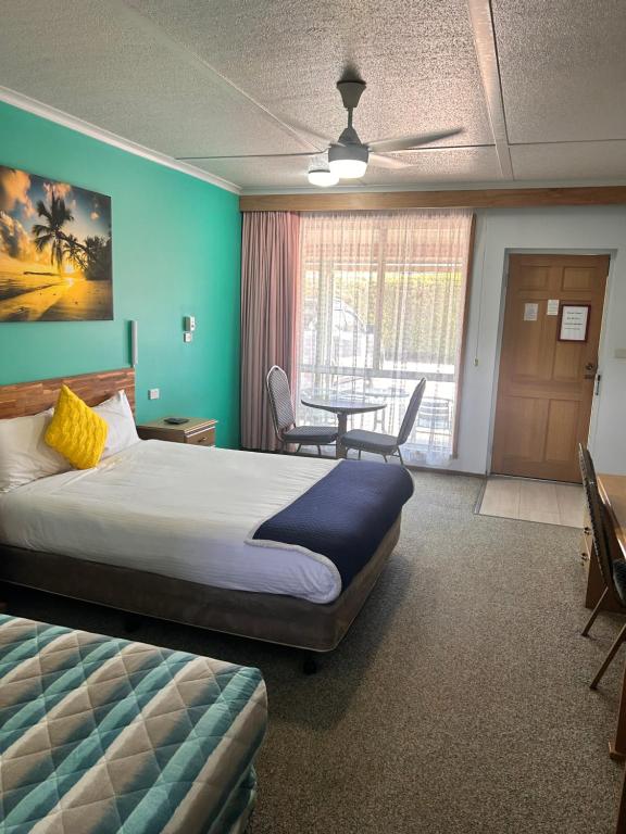 a hotel room with a bed and a table at Acacia Rose Motor Inn in Barham