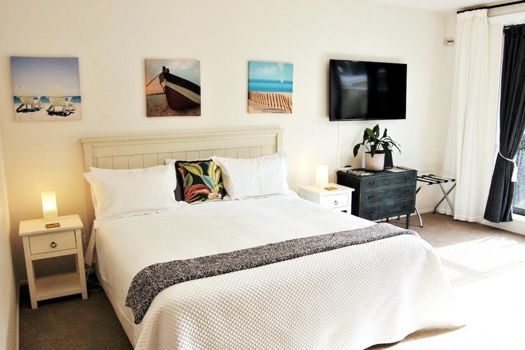 a bedroom with a white bed and a flat screen tv at Pacific Paradise Apartment in Tutukaka