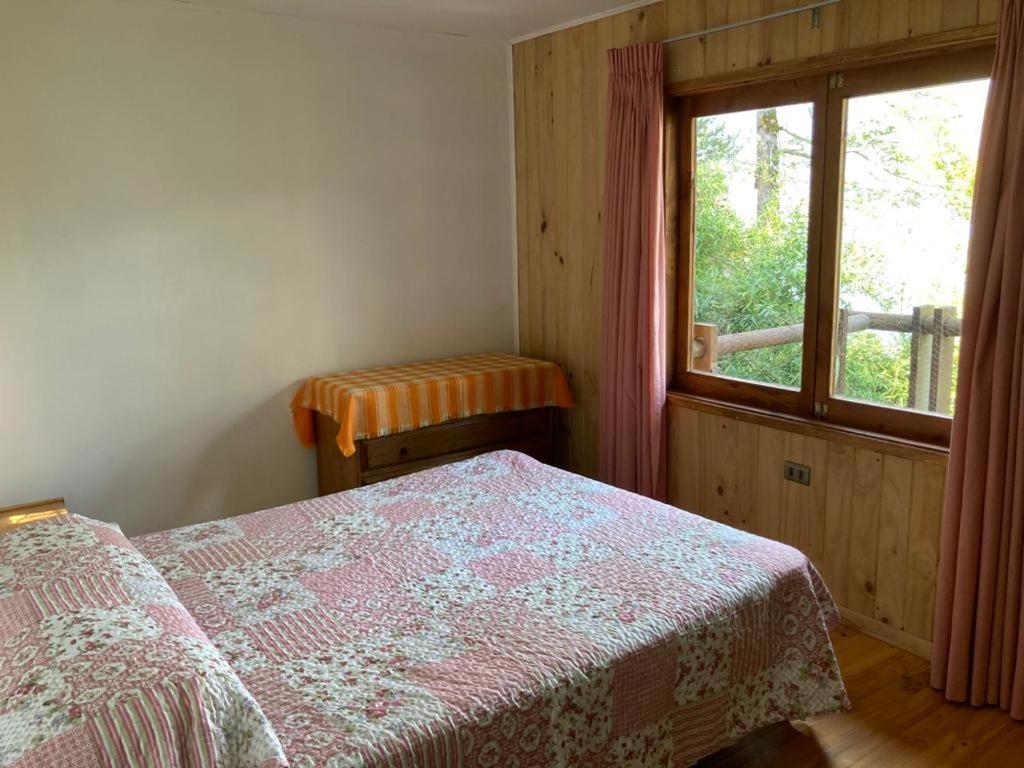 een slaapkamer met een bed en een raam bij Cabaña Yoka - Orilla de Lago in Pucura
