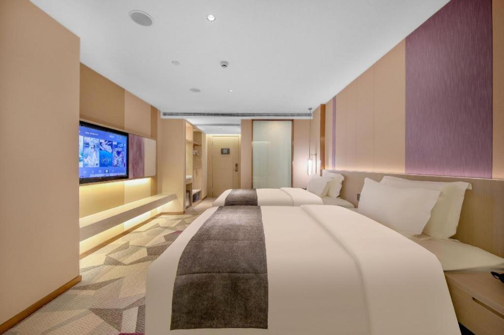 a large bedroom with two beds and a flat screen tv at Lavande Hotel Wuhan Jianghan Road Dunli Gate Metro Station in Wuhan