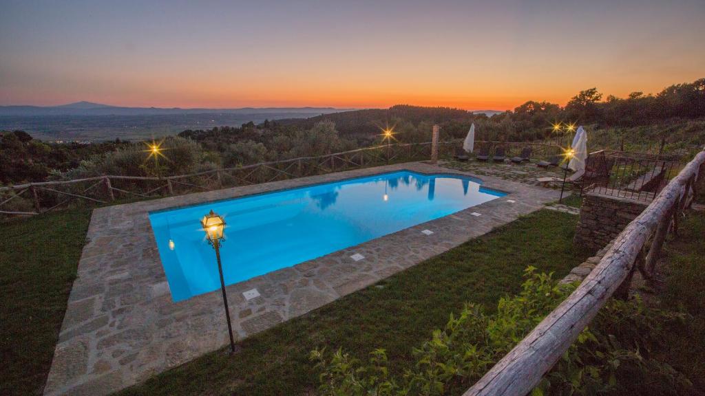 コルトーナにあるTenuta Angelici Winery Agriturismo Henni with pool sauna and jacuzzi Cortonaの夕日を背景に見えるスイミングプール