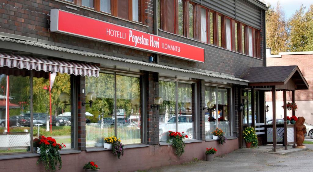 una tienda frente a un edificio con flores en las ventanas en Hotelli Pogostan Hovi en Ilomantsi