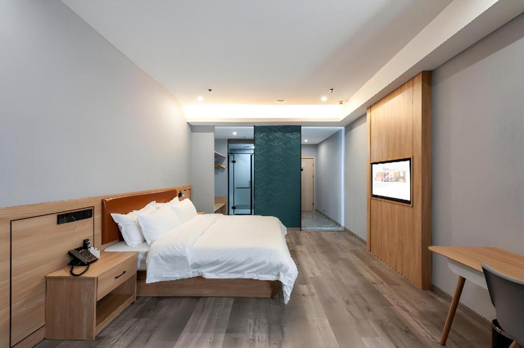 ein Hotelzimmer mit einem Bett und einem Schreibtisch und einem Schreibtisch in der Unterkunft Borrman Hotel Jiangyin Zhouzhuang in Xiwujieqiao