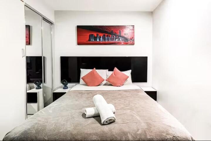 Cozy Studio in the heart of CBD C4 في بريزبين: غرفة نوم بسرير كبير مع وسائد حمراء