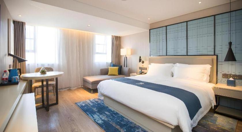 ein Schlafzimmer mit einem großen weißen Bett und einem Schreibtisch in der Unterkunft Echarm Hotel Shenzhen World Exhibition and Convention Center in Fenghuangwei