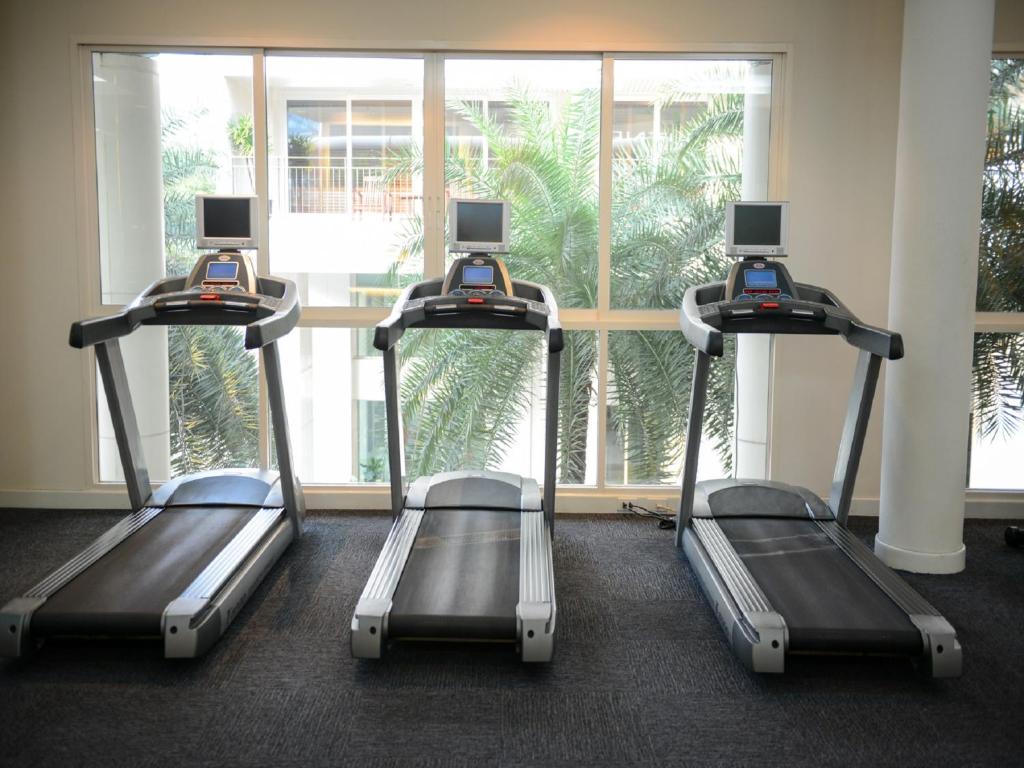 Three treadmills positioned in front of a large window.