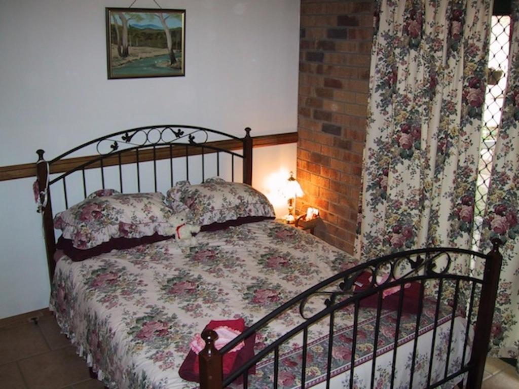a bedroom with a bed with a floral bedspread at Twilight Grove Farm in Esk