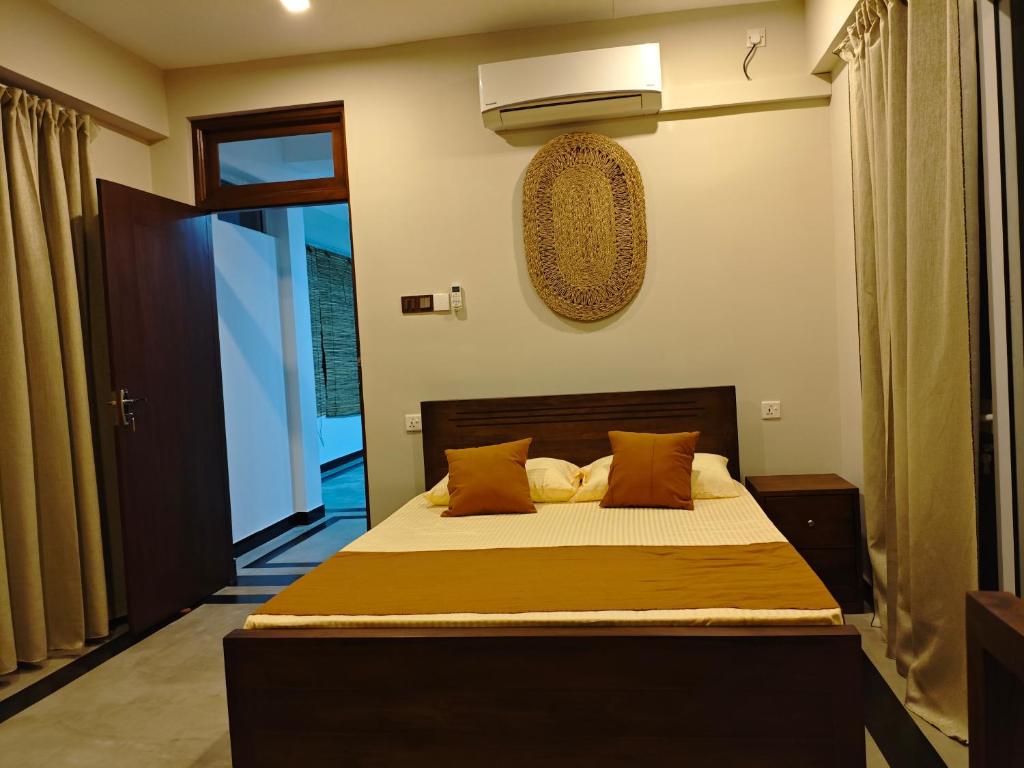 a bedroom with a bed with orange pillows at Lagoonai Villa in Sinimodera