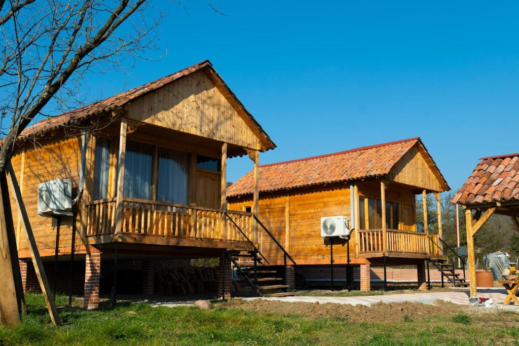 Sunrise Gelati في Motsameta: منزل خشبي مع شرفة وساحة كرة سلة