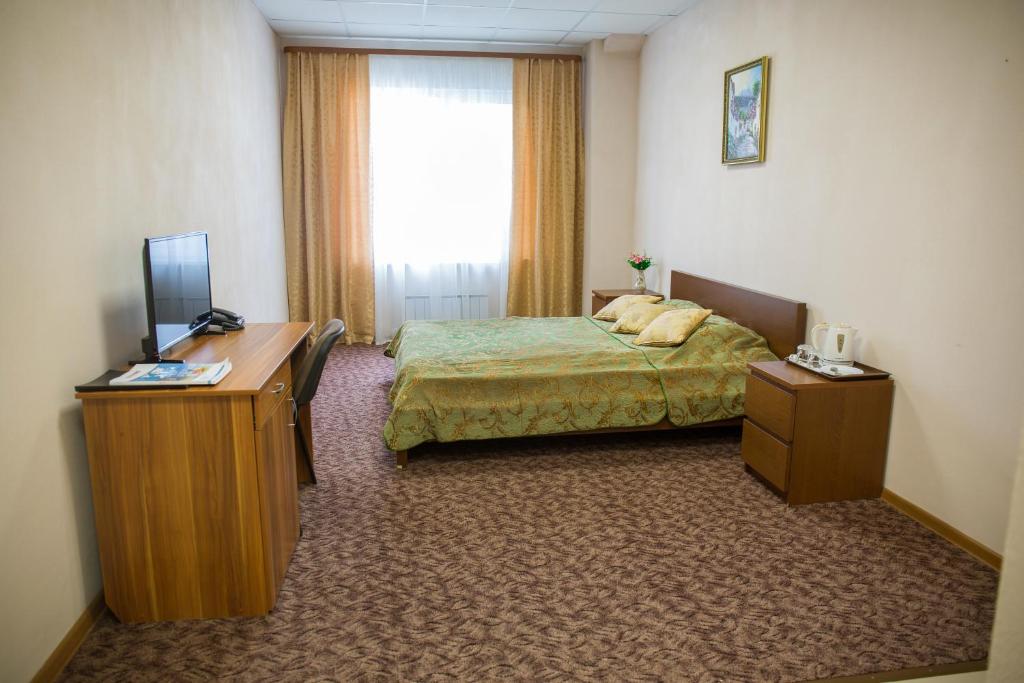 Aramil'にあるHotel & Hostel Kleverのベッドとデスクが備わるホテルルームです。
