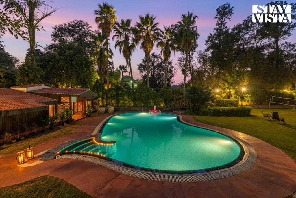 a swimming pool in a yard with a house at StayVista at The Birdwood Estate with Gym and Pool in New Delhi