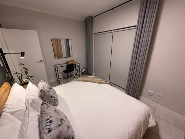 Luxury Coastal Escape in Strand في Somerset West: غرفة نوم بها سرير مع ملاءات ووسائد بيضاء