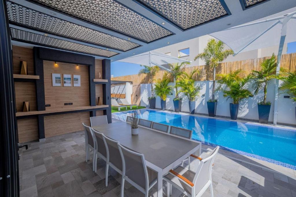 a dining room with a swimming pool and a table and chairs at Villavender Boutique Suites in Netivot