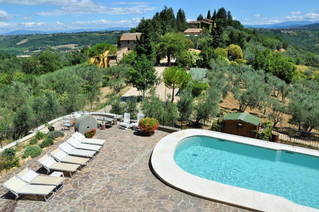a swimming pool with lounge chairs and a resort at Agriturismo La Villa Romita in Tavarnelle in Val di Pesa
