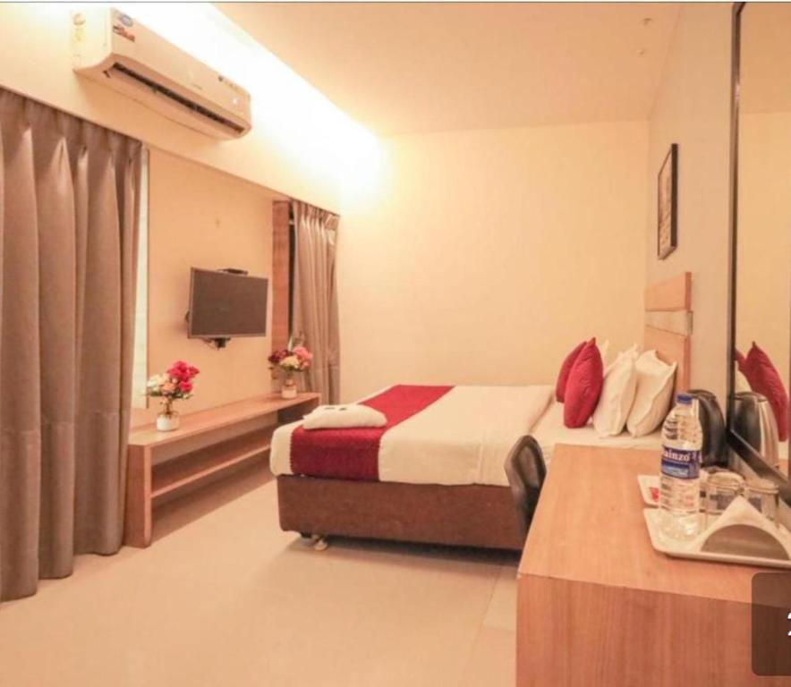 ムンバイにあるHotel AI inのベッドとテレビがあるホテルの部屋