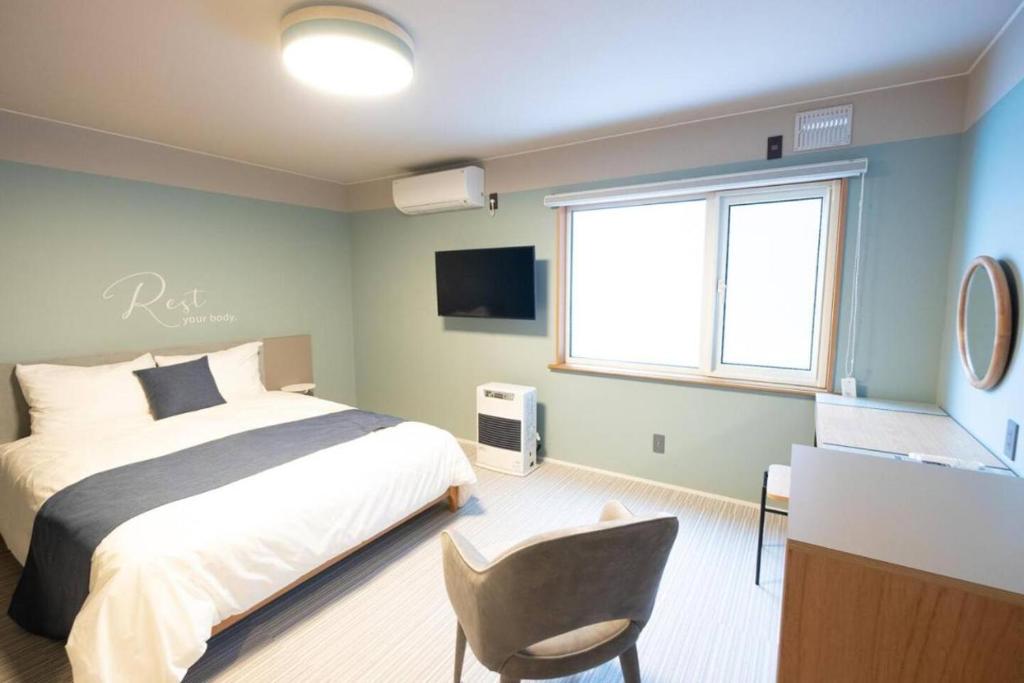 a bedroom with a bed and a desk and a window at B cycle Double Room in Biei