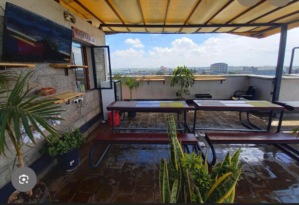 een terras met tafels en potplanten op een dak bij adtek homes Room PENDO in Nairobi