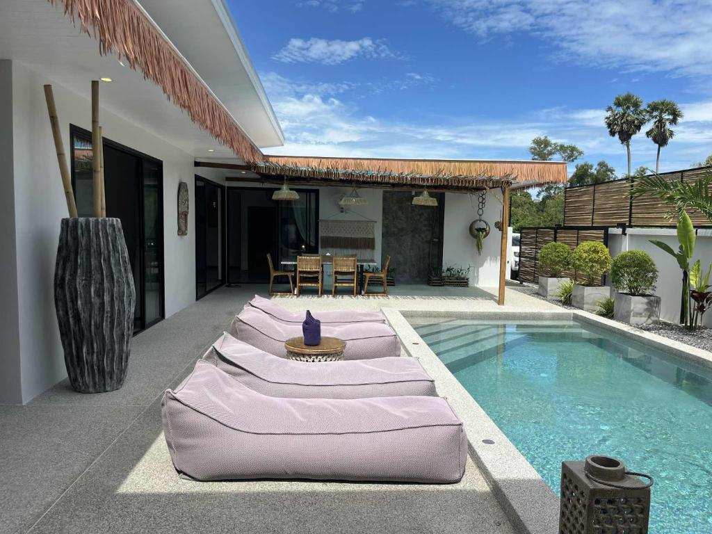una fila di cuscini seduta accanto alla piscina di Villa ANSEJU Tranquillité, Jardin Tropical & 3 Chambres Spacieuses a Hua Thanon Beach