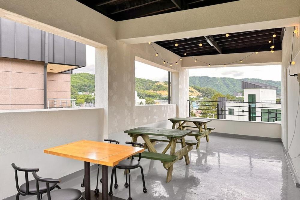 two tables and chairs in a room with windows at Janghohang Ilmare Pension in Samcheok
