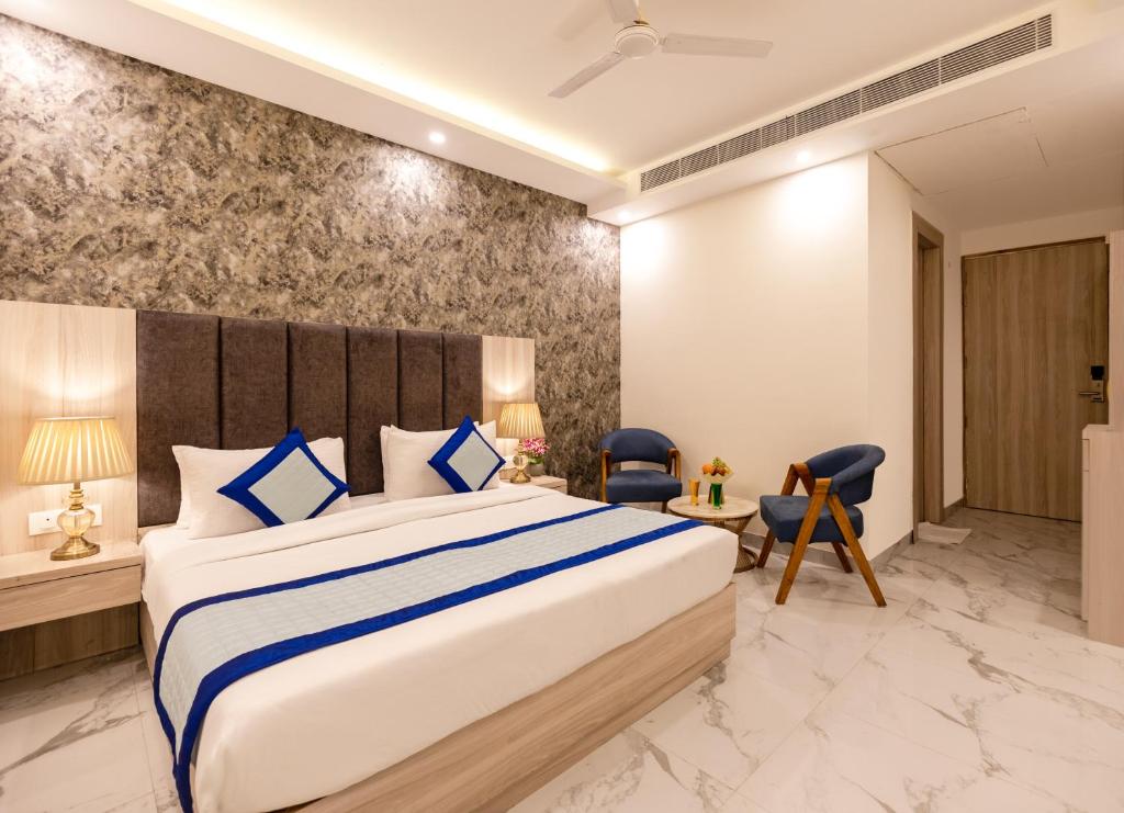 a bedroom with a large bed with blue pillows at Hotel The Grand Bharath in New Delhi