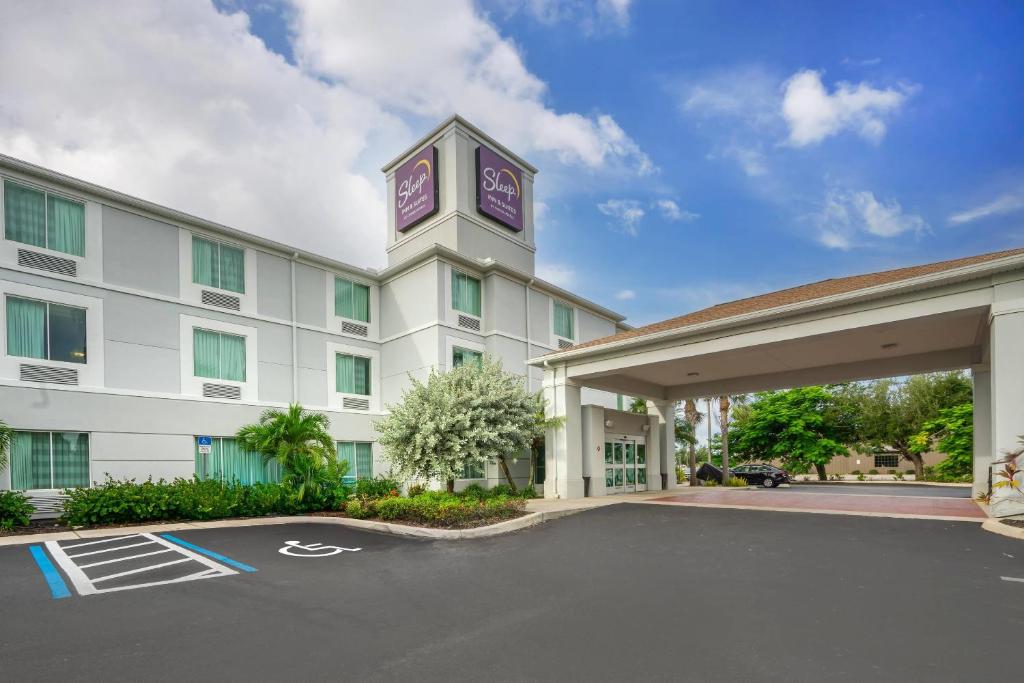 un hotel con una torre dell'orologio in un parcheggio di Sleep Inn & Suites Port Charlotte-Punta Gorda a Port Charlotte