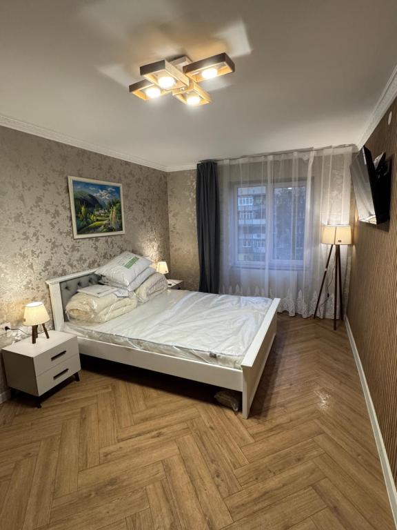 a bedroom with a large bed and a window at Prestige Apartament near thermal pool in Berehove