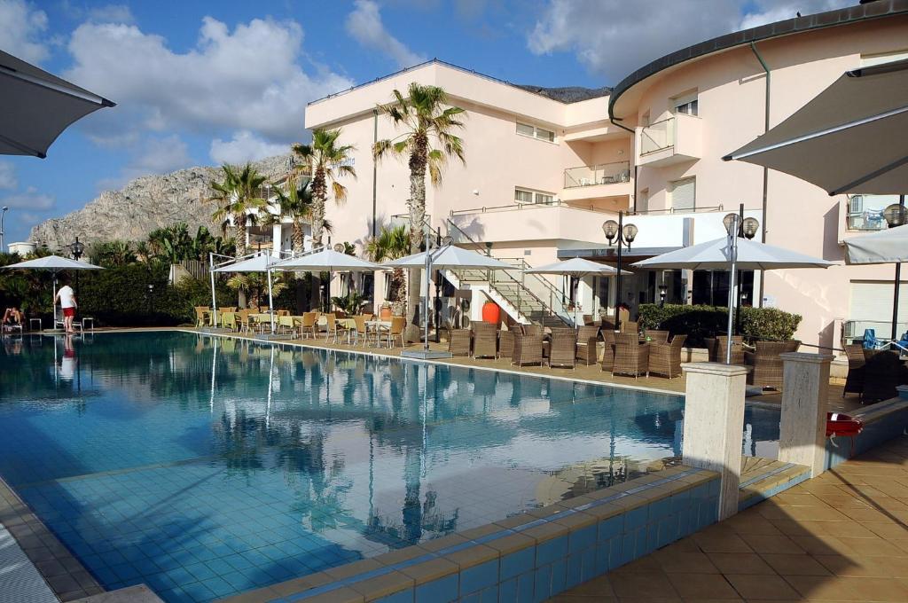 una piscina con sedie e ombrelloni accanto a un edificio di Hotel Sirenetta a Isola delle Femmine