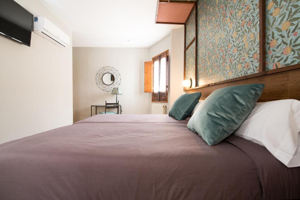 a bedroom with a large bed with green pillows at Hotel Sol in Toledo