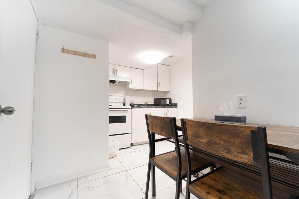 a white kitchen with a wooden table and chairs at Cozy Private 2 bedroom apartment, free Wifi, free parking in heart of Toronto, surrounded by nature in Toronto