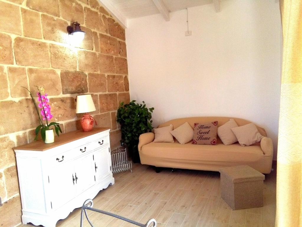 salon z kanapą i ścianą z cegły w obiekcie La Casetta Holiday Home w mieście Alghero