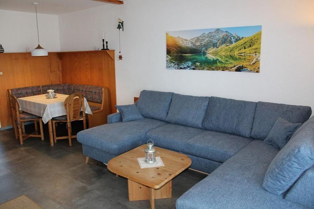 Ferienhaus Nr 125, Kategorie Economy, Feriendorf Hochbergle, Allgäu في Karlsebene: غرفة معيشة مع أريكة زرقاء وطاولة