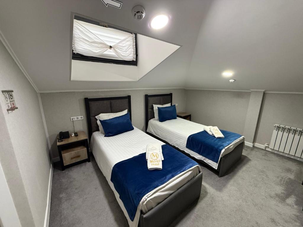 YakkasarayMerci in Tashkent Hotel的一间卧室，有两张床，床单是蓝色的，还有一扇窗户