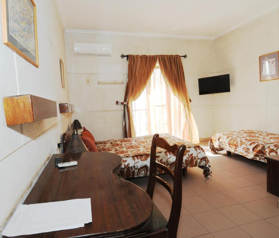 a hotel room with a desk and a room with two beds at Hotel de La Poste in Saint-Louis