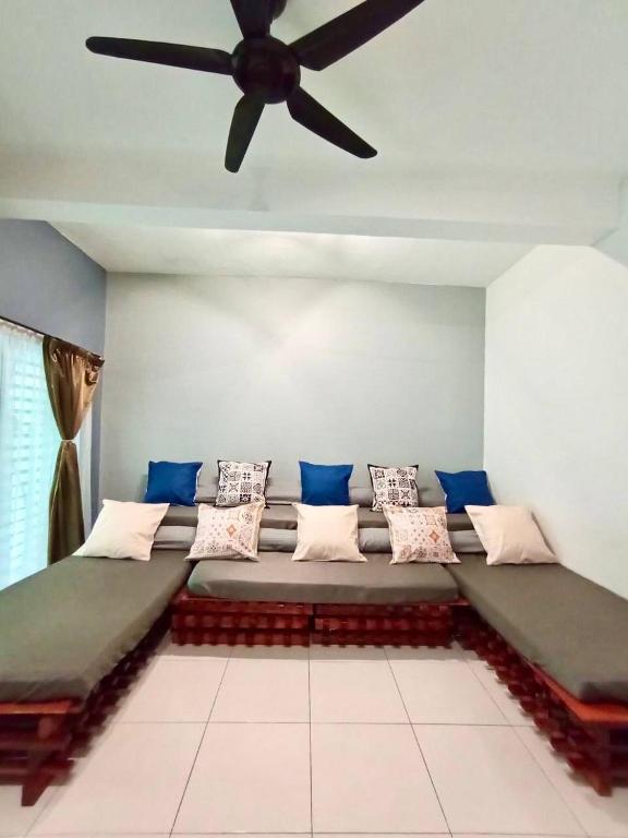 a couch in a room with a ceiling fan at Animation Homes I Meru Raya IPOH I by Grab A Stay l 16pax max in Ipoh