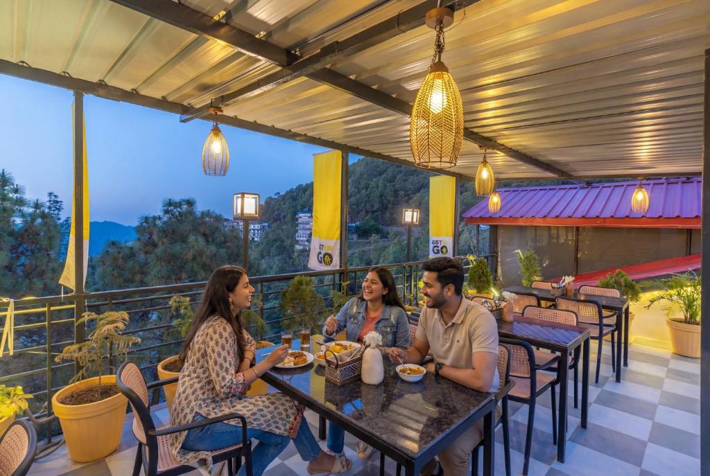 eine Gruppe von Menschen, die an einem Tisch auf einer Terrasse sitzen in der Unterkunft The Hosteller Kasauli in Kasauli
