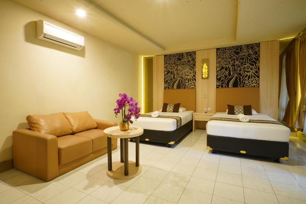 a hotel room with two beds and a couch at Hotel Grand Rosela in Yogyakarta