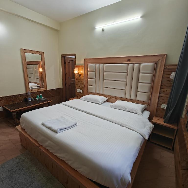 a bedroom with a large bed with white sheets at Qpoint hotel in Kasol