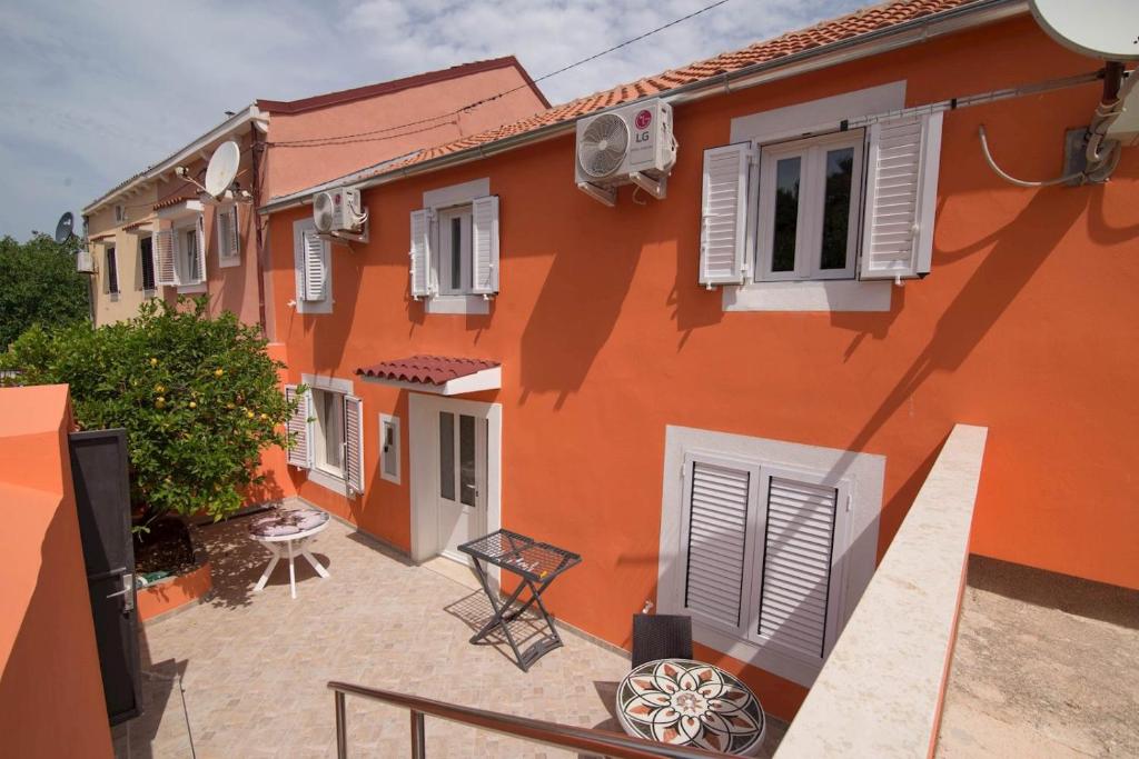 an orange house with white shutters and a patio at Luisa S2 room B in Veli Lošinj