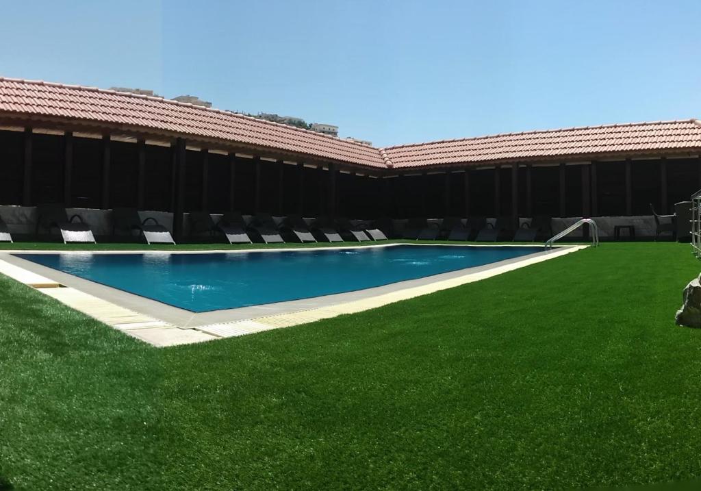 a swimming pool with green grass next to a building at Seven Wonders Hotel in Wadi Musa