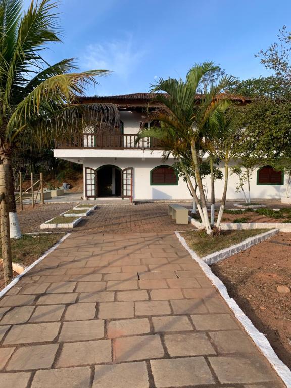 una casa con delle palme davanti di Pousada Flat Royal Suíte com varanda e rede a Itapecerica