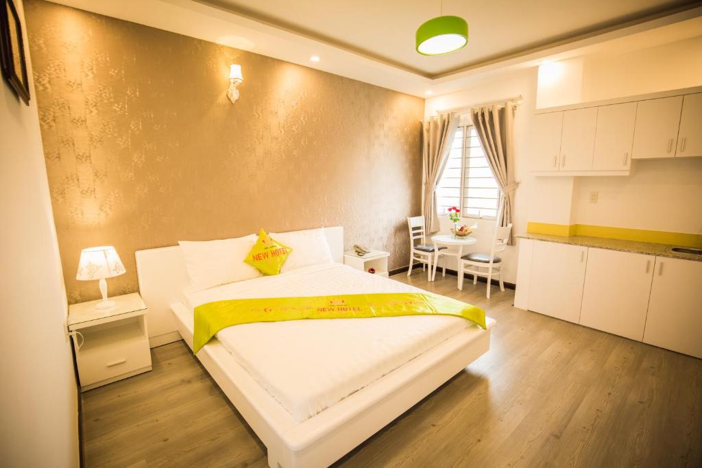 a bedroom with a large white bed and a kitchen at New Hotel & Apartment in Thu Dau Mot