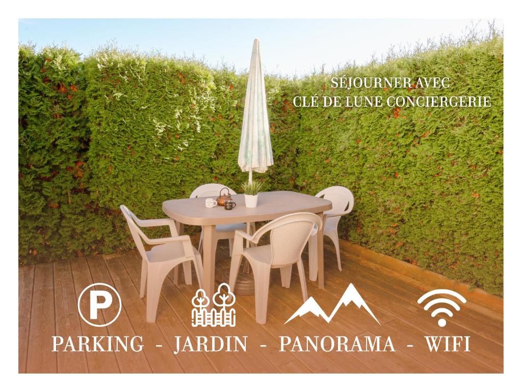 einen Tisch mit Stühlen und einem Sonnenschirm auf einer Terrasse in der Unterkunft Terrasse des Monts - Duplex Indépendant de Charme in Les Hôpitaux-Neufs