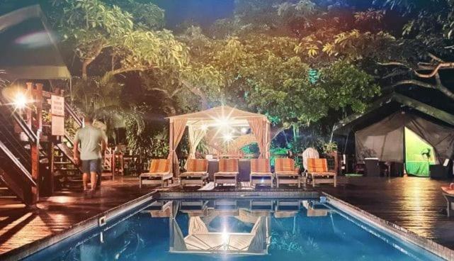 um homem parado em frente a uma piscina em Luxury Tented Village @ Urban Glamping em St Lucia