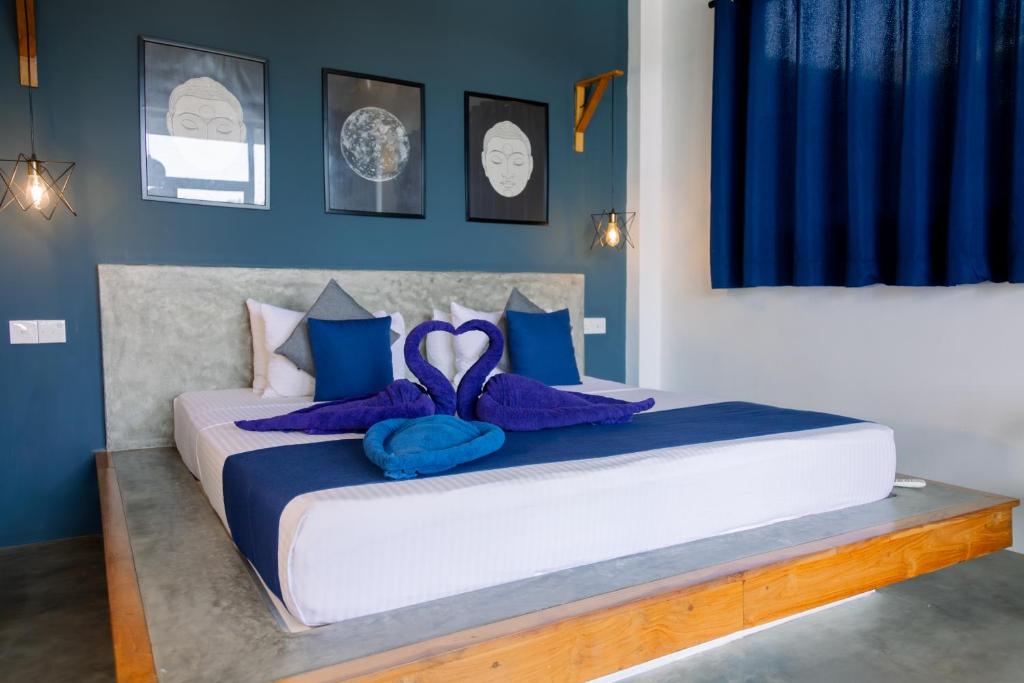 a bedroom with a large bed with blue and purple pillows at Haven Beach Hiri - Hiriketiya in Dickwella