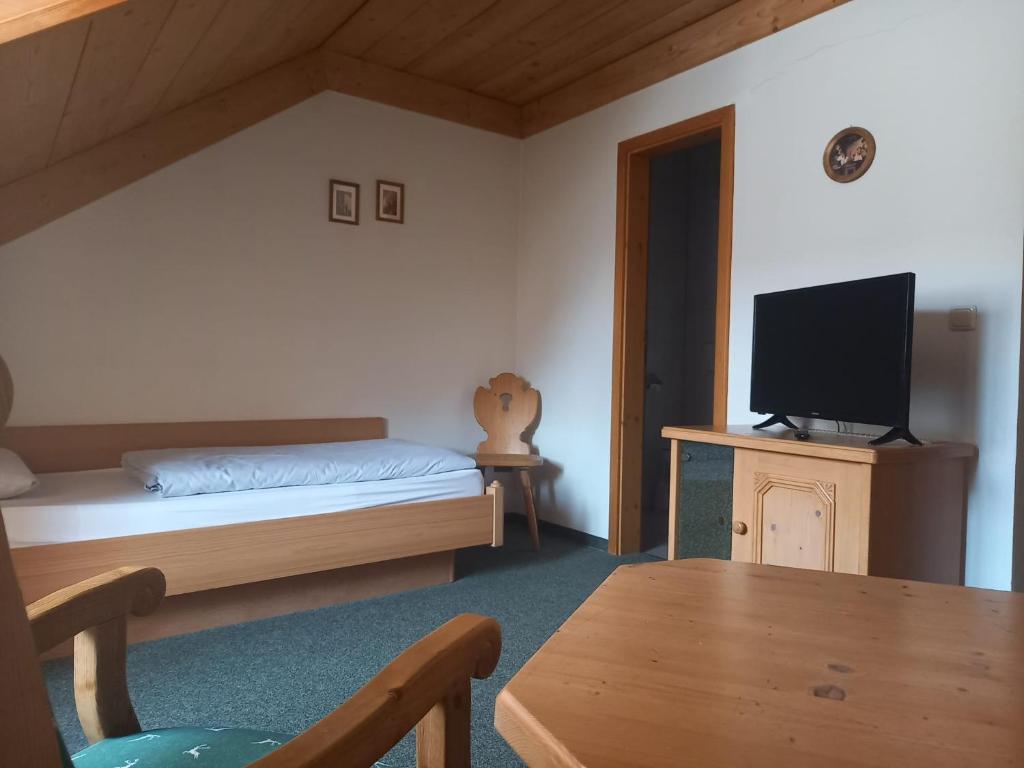 Un dormitorio con una cama, un televisor y una mesa. en Hotel Gästehaus Gross, en Aschheim