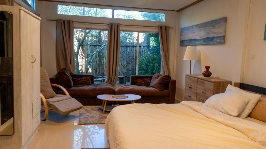 um quarto com uma cama, um sofá e uma mesa em Bamboo House em Laguna Phuket